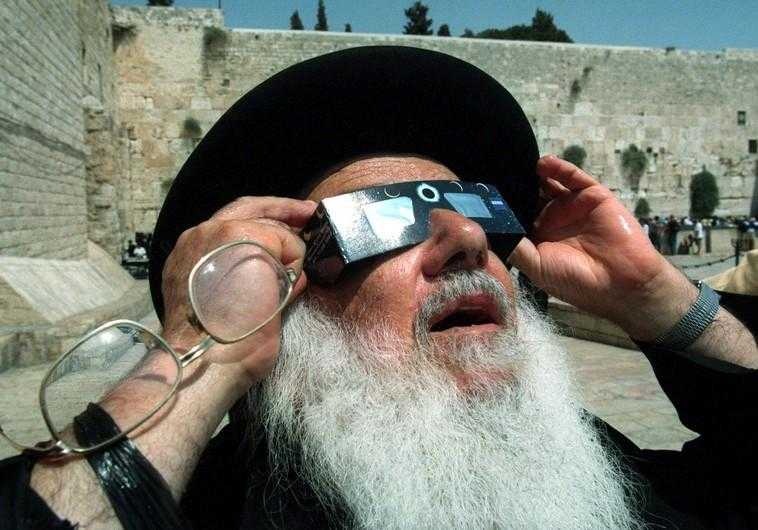 An ultra-Orthodox Jewish rabbi holds up a pair of special glasses as he views the last solar eclipse of the millennium August 11 in front of the Western Wall. August, 1999